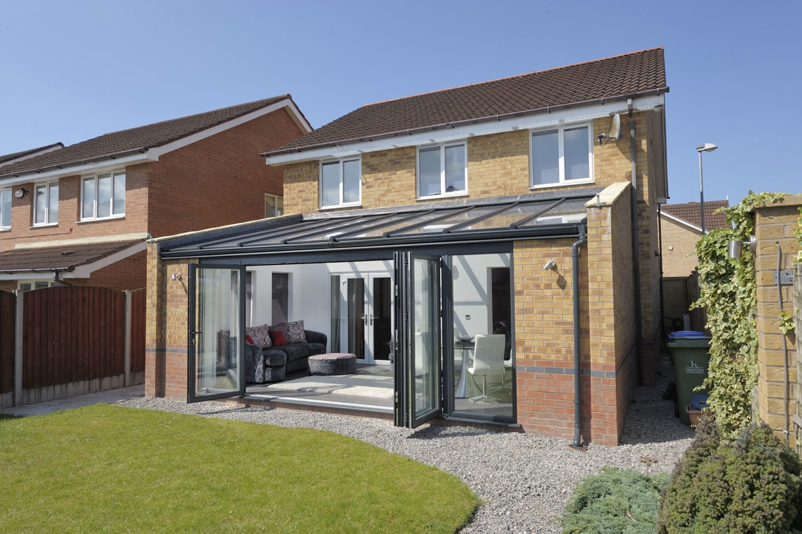 Contemporary lean-to conservatory showcasing sleek lines and large glass windows, providing a bright and airy space that seamlessly extends from the home into the garden, enhancing the property's modern aesthetic.