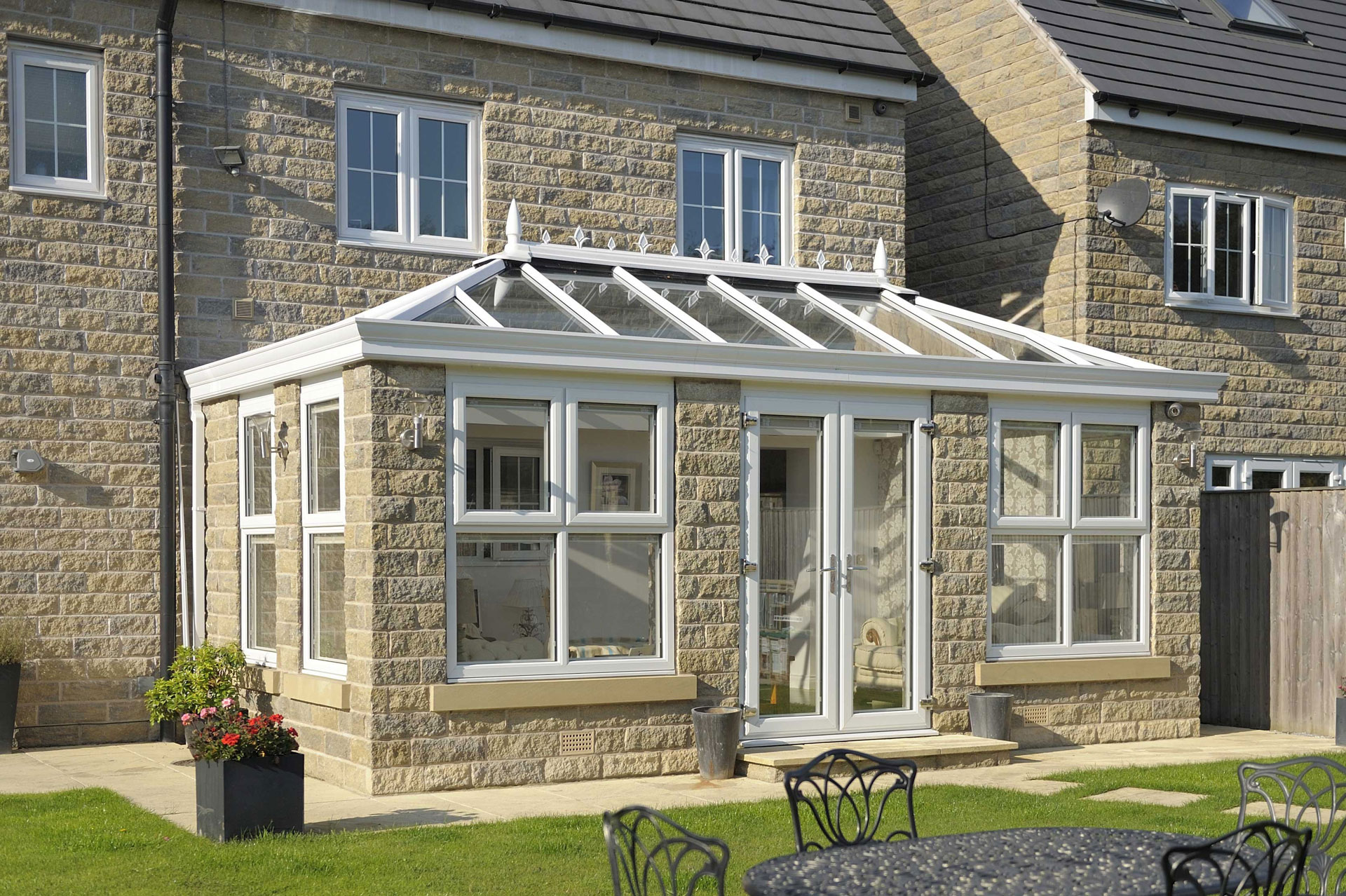 An orangery on the back of a large stone built house.