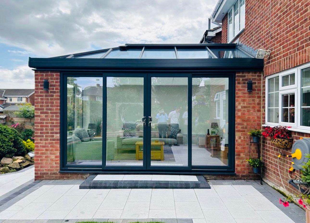 Elegant interior of a conservatory featuring comfortable furniture, tasteful decor, and ample natural light streaming through large windows, creating a cozy and inviting space.