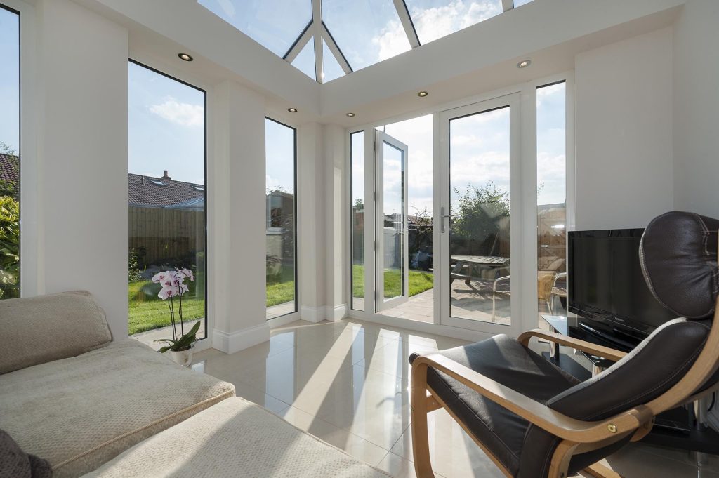 Modern glass-to-floor conservatory showcasing expansive, floor-to-ceiling glass panels that provide an unobstructed view of the outdoors, creating a seamless integration between the interior space and the natural environment outside.