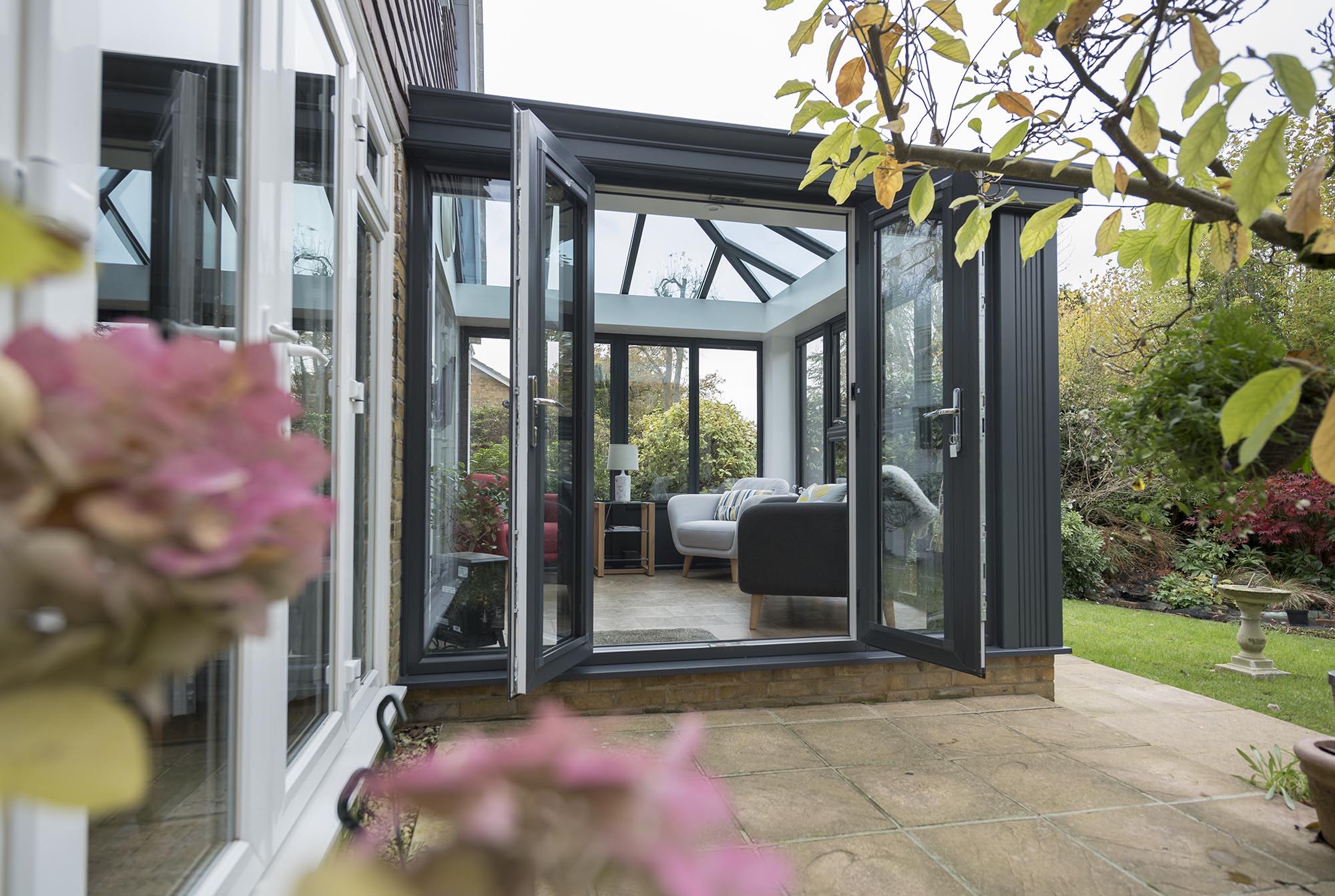 Contemporary conservatory with an impressive glass-to-roof design, showcasing a transparent ceiling that extends to the walls, allowing for an abundance of natural light and providing a spacious, open atmosphere with a full view of the sky and surrounding landscape.