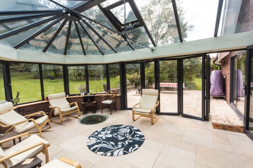 open planned bespoke conservatory with a glass roof and sides and bifold doors