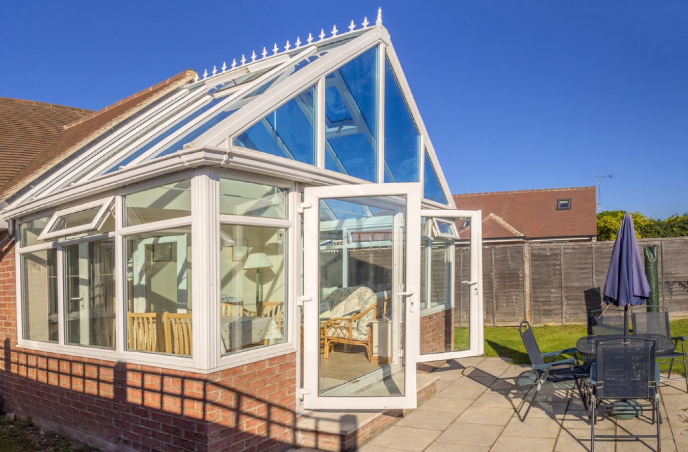 white upvc gable end conservatory with wide open white upvc french doors