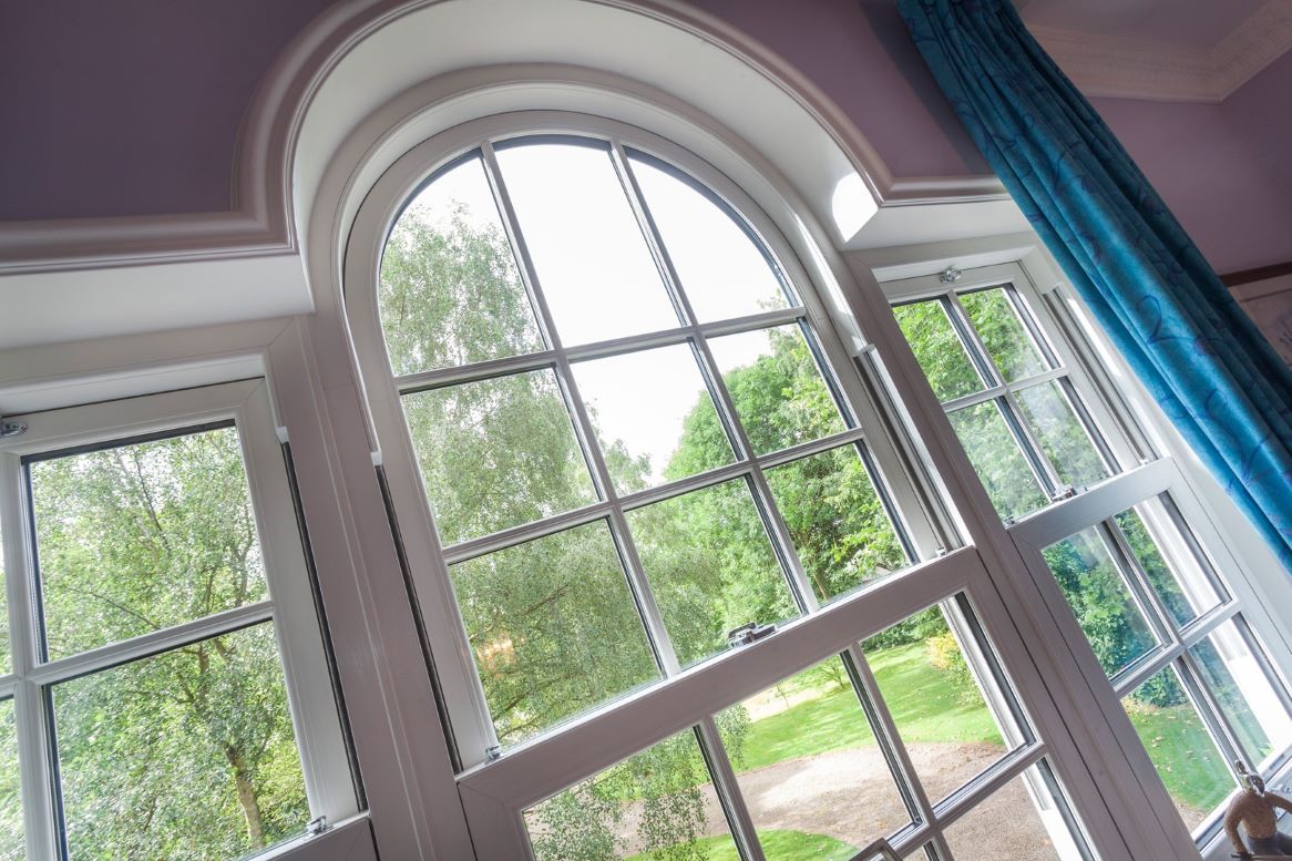 internal close-up of white upvc sliding sash windows with large green trees in the background